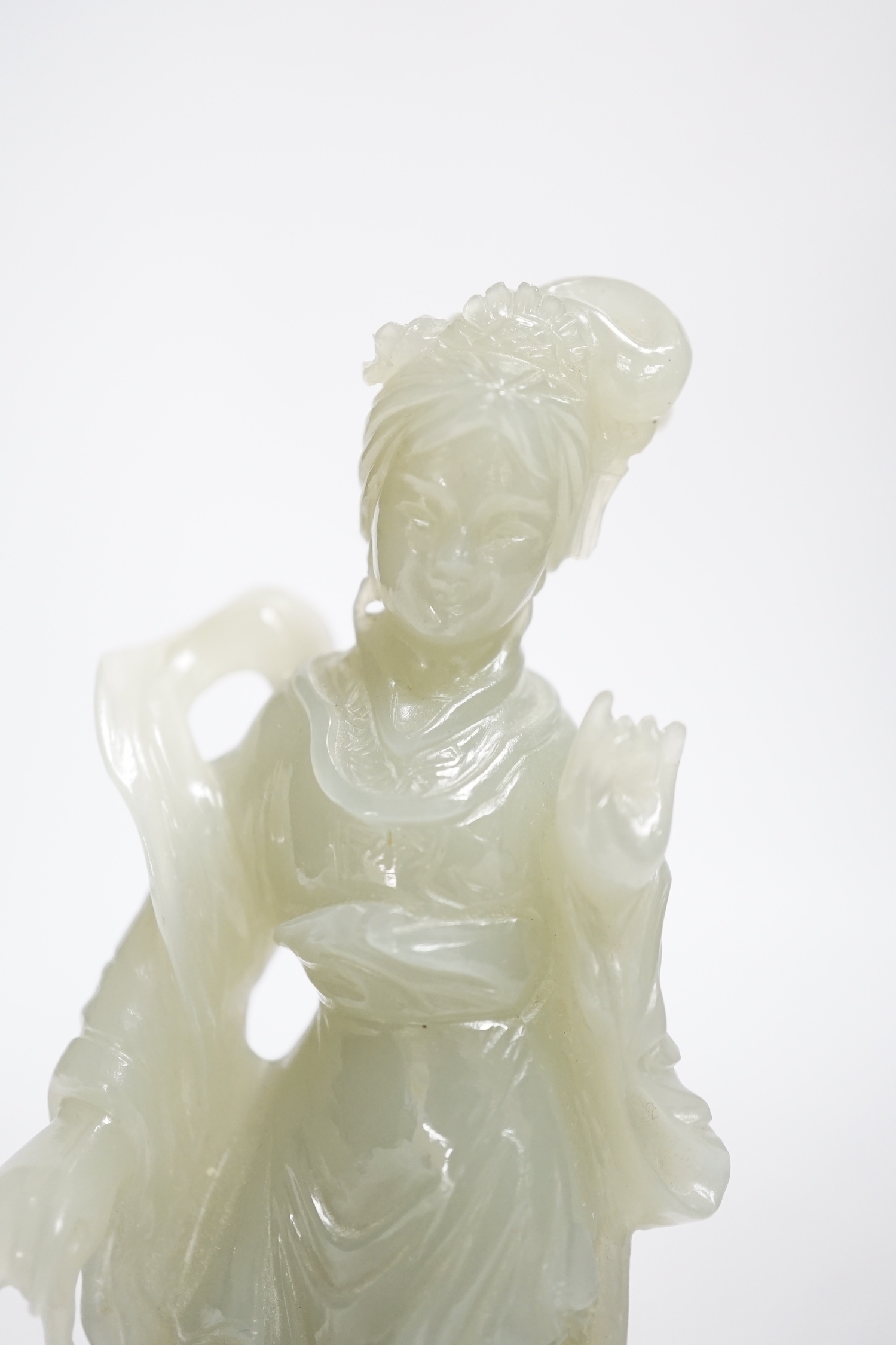 A Chinese celadon jade figure of a lady, on wood stand, 13cms high.